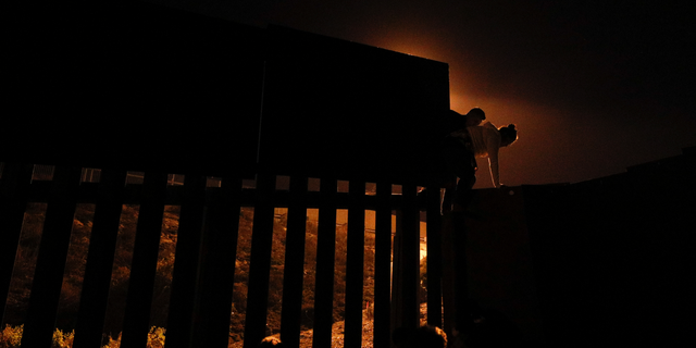 FILE - In this Dec. 2, 2018, file photo, Honduran migrants climb over a section of the U.S. border fence from Playas of Tijuana, Mexico, before handing themselves in to border control agents. A surge in family arrivals, largely from Guatemala and Honduras, has led Border Patrol agents to shift attention from preparing criminal cases to caring for children. (AP Photo/Rebecca Blackwell, File)