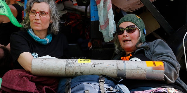 Protesters chained themselves onto a boat in Oxford Circus in London on Friday as part of the ongoing climate action-related demonstrations. (AP)
