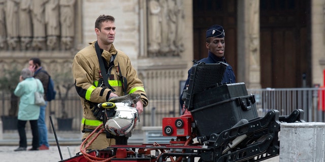 Firefighters are seen with a robot firefighter called Colossus, made by French robotics company Shark Robotics, outside Notre-Dame Cathedral after a major fire on April 16, 2019.