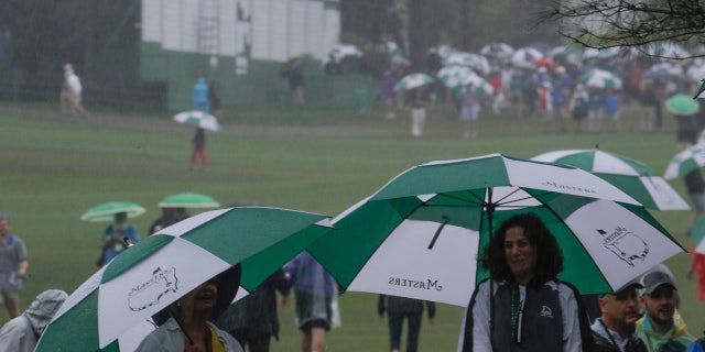 Fans use umbrellas near the ninth hole during the second round for the Masters golf tournament Friday, April 12, 2019, in Augusta, Ga. (AP Photo/Charlie Riedel)