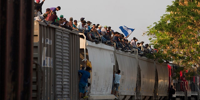 Central American migrants ride atop a freight train during their journey toward the U.S.-Mexico border, in Ixtepec, Oaxaca State, Mexico, on Tuesday.