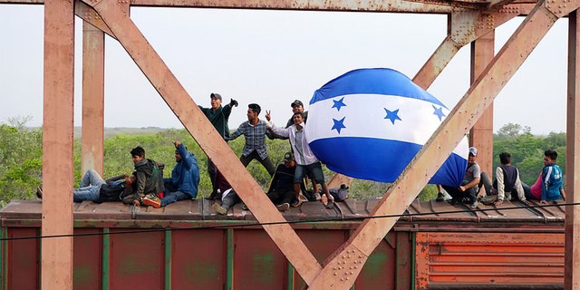 Central American migrants hold Honduras' national flag, while moving in a caravan through Juchitan, Oaxaca atop a train known as "The Beast" towards the United States, in Mexico April 26, 2019.