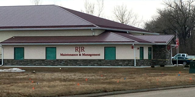 Cars are parked outside RJR Maintenance and Management in Mandan, N.D., on Monday, April 1, 2019. Police in North Dakota said 4 bodies were been found inside the business in suburban Bismarck.
