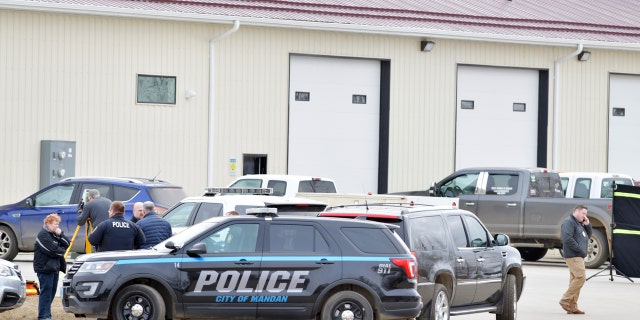 Law enforcement officers stand outside RJR Maintenance and Management in Mandan, North Dakota on Monday, where four people were found dead.