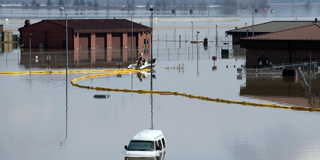 Environmental restoration employees deploy a containment boom from a boat on Offutt Air Force Base in Neb., as a precautionary measure for possible fuel leaks in the flooded area.
