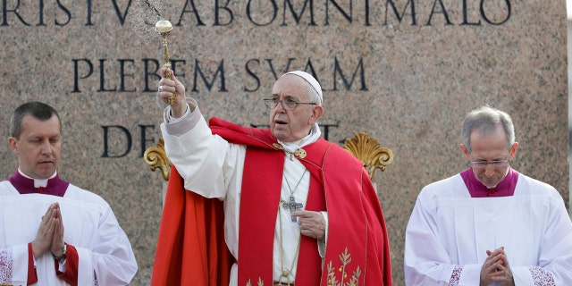 Pope Francis asperses holy water as he celebrates Palm Sunday Mass in St. Peter's Square at the Vatican, Sunday, April 14, 2019.