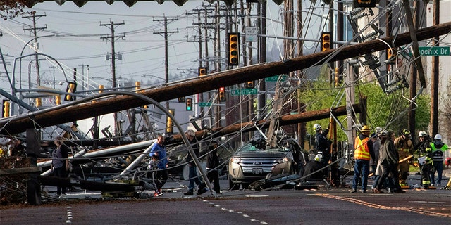 Two people were trapped in the SUV for about an hour after several power poles came crashing down on East Marginal Way on Friday, according to Tukwila police. (Ellen M. Banner/The Seattle Times via AP)