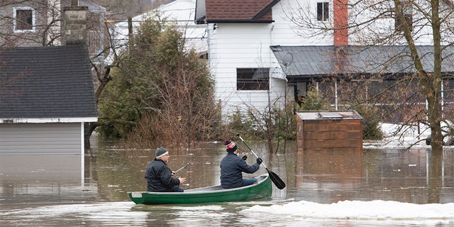 People paddle a canoe on the flooded streets in Sainte-Marie, Quebec, Saturday, April 20, 2019. The Chaudiere River burst its banks after heavy rain.