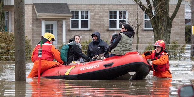 People are evacuated by firefighters in a boat in Sainte-Marie, Quebec, Saturday, April 20, 2019. The Chaudiere River burst its banks after heavy rain.