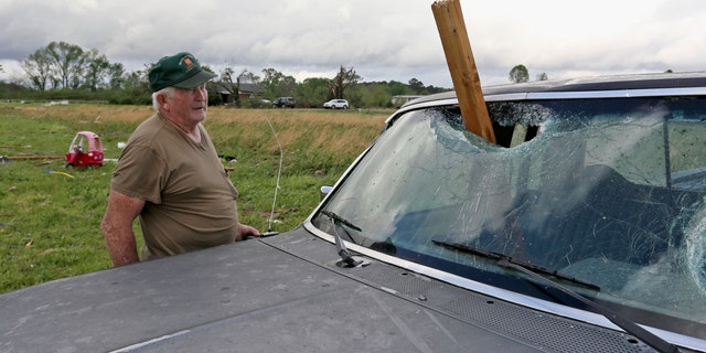 A man looks at a piece of wood that was blown through the windshield of his daughter's truck in Hamilton, Missouri, after a storm hit the area on Sunday, April 14th. 2019.