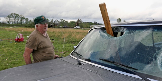 A man looks at a piece of wood that was blown through the windshield of his daughter's truck in Hamilton, Missouri, after a storm hit the area on Sunday, April 14th. 2019.