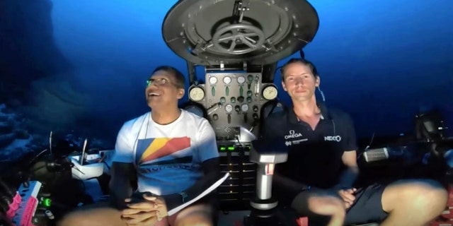 An image taken from video issued by Nekton shows Seychelles President Danny Faure, left, smiles after speaking from inside a submersible from the vessel Ocean Zephyr, under the water off the coast of Desroches, in the outer islands of Seychelles Sunday, April 14, 2019. (Nekton via AP)