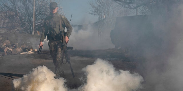 A Ukrainian serviceman makes smokescreen against military drones at a position near the front line as the conflict continues, in Mariinka, Donetsk region, eastern Ukraine, Saturday, April 20, 2019.