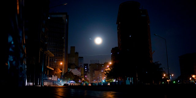 The moon rises above an empty avenue in Caracas, Venezuela, late Thursday, March 21, 2019. Residents avoid stepping outside their homes due to crime, or for lack of anything to spend. (AP Photo/Natacha Pisarenko)