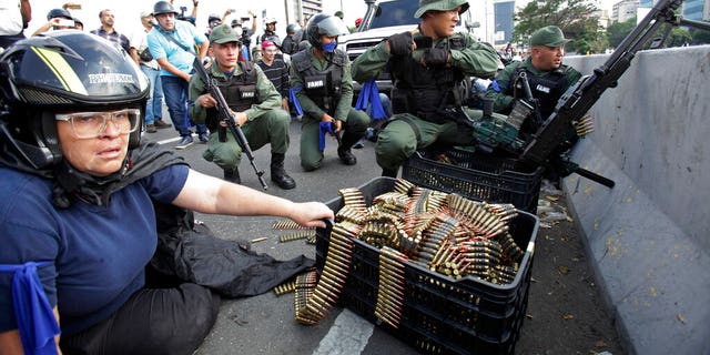 An anti-government protester sits by ammunition being used by rebel troops rising up against the government of Venezuela's President Nicolas Maduro as they all take cover on an overpass outside La Carlota military airbase where the rebel soldiers confront loyal troops inside the base in Caracas, Venezuela.