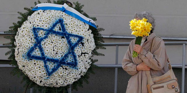 Warsaw residents carry daffodils, which have become the symbol of remembrance of the 1943 Warsaw Ghetto Uprising against the German Nazi, during anniversary observances in Warsaw, Poland, Friday, April 19, 2019.(AP Photo/Czarek Sokolowski)