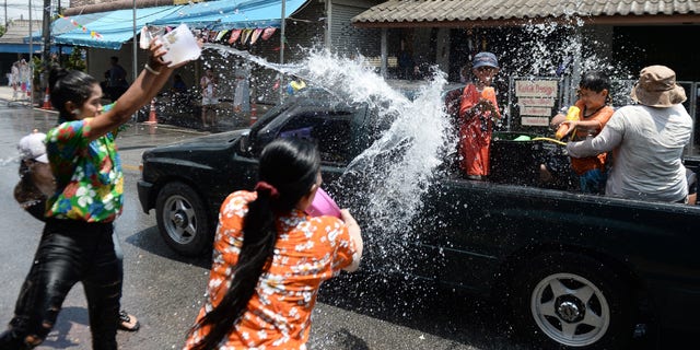 Revelers throw water on passing motorists as they celebrate Songkran, also known as the Thai New Year, in Narathiwat on April 13, 2019.