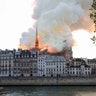 Seen from across the Seine River, smoke and flames rise during the fire.