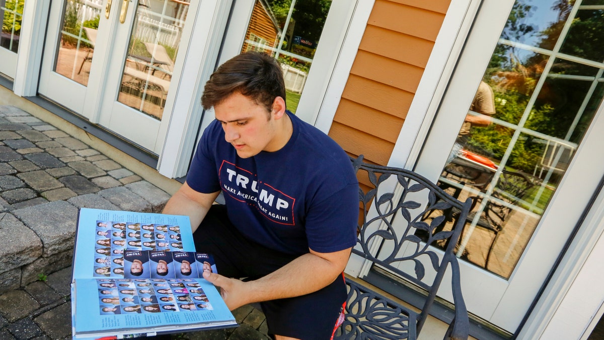 In this June 2017 photo, Wall High School student Grant Berardo is seen flipping through his 2017 school yearbook. The yearbook included a photo of him wearing a digitally altered T-shirt that originally included the words "Trump Make America Great Again."