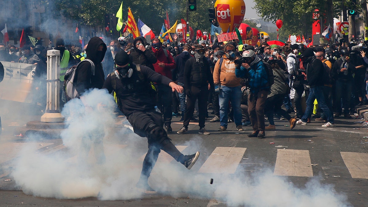 An activist kicks away a tear gas canister during a May Day demonstration in Paris. (AP Photo/Francois Mori)