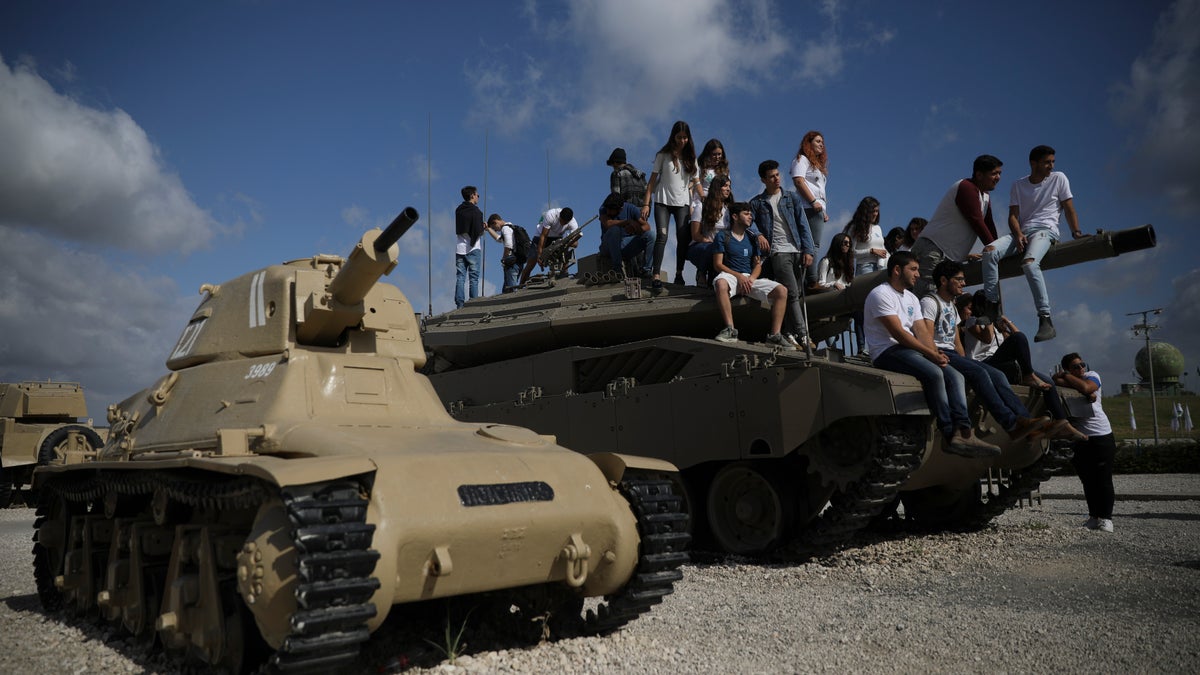 Students sit on a tank just before a ceremony marking the annual Memorial Day to remember fallen soldiers and victims of terror, at the Armored Corps memorial site in Latrun, Israel, Wednesday, May 8, 2019. (AP Photo/Oded Balilty)
