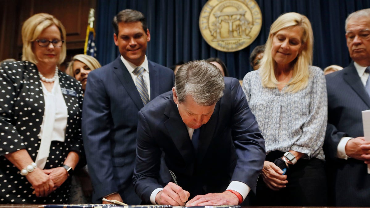 FILE - In this May 7, 2019, file photo, Georgia's Republican Gov. Brian Kemp, center, signs legislation in Atlanta, banning abortions once a fetal heartbeat can be detected, which can be as early as six weeks before many women know they're pregnant. Georgia became the fourth state to enact the ban on abortions after a fetal heartbeat can be detected. (Bob Andres/Atlanta Journal-Constitution via AP, File)