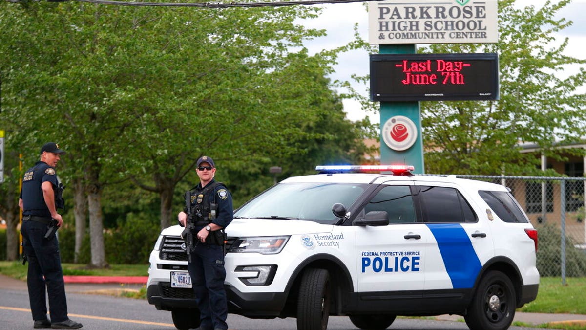 Police are positioned outside Parkrose High School during a lockdown after a man, said to be armed, was wrestled to the ground by a staff member on Friday. The Portland Police Bureau said in a statement Friday that no shots were fired and a suspect is in custody. (Dave Killen/The Oregonian via AP)