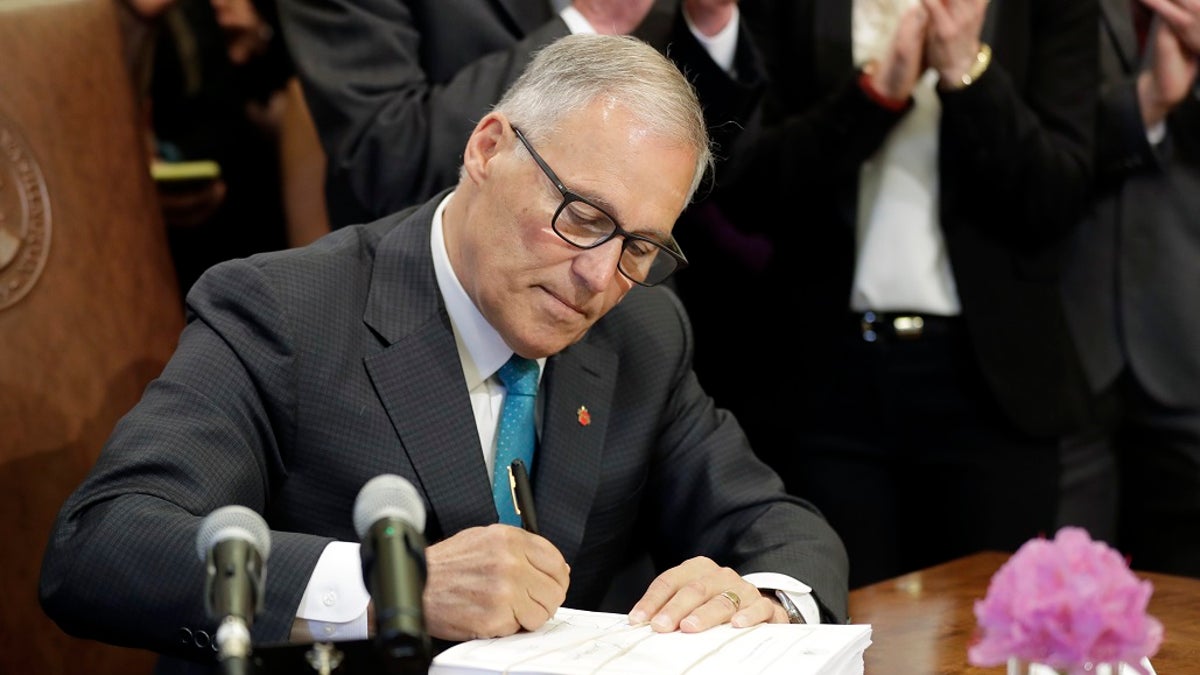 Washington Gov. Jay Inslee signs the state operating budget, Tuesday, May 21, 2019, at the Capitol in Olympia, Wash. Inslee also signed a “sanctuary state” measure on Wednesday. (AP Photo/Ted S. Warren)