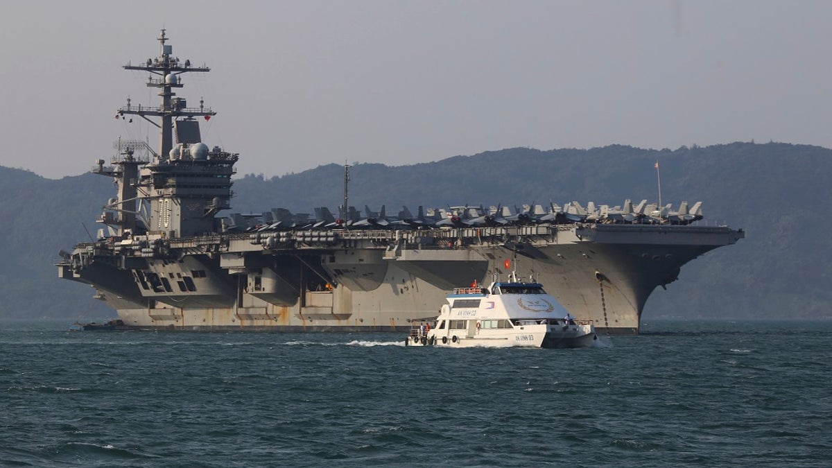 In this March 5, 2018, file photo, a Vietnamese passenger boat sails past U.S. aircraft carrier USS Carl Vinson as it docks in Danang bay, Vietnam. A U.S. sailor has pleaded guilty to espionage and sentenced to three years after admitting he took classified information about a Navy's nuclear-powered warship and planned to give it to a journalist and then defect to Russia officials said Friday, (AP Photo/Hau Dinh, File)