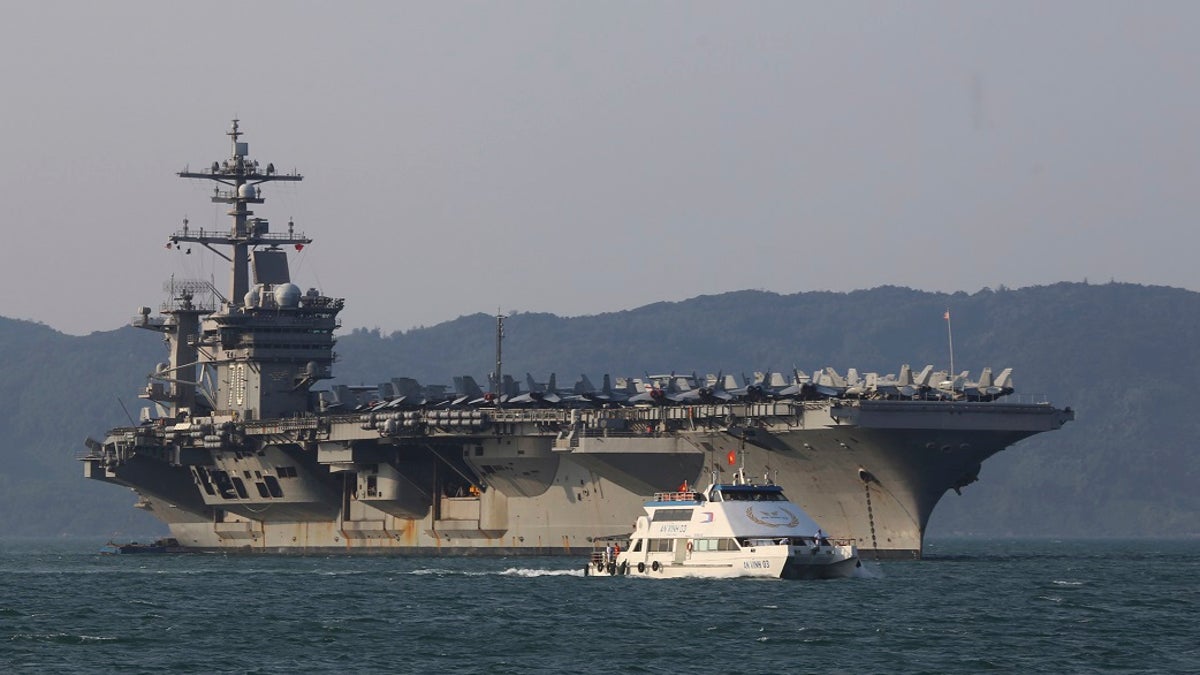 In this March 5, 2018, file photo, a Vietnamese passenger boat sails past U.S. aircraft carrier USS Carl Vinson as it docks in Danang bay, Vietnam. A U.S. sailor has pleaded guilty to espionage and sentenced to three years after admitting he took classified information about a Navy's nuclear-powered warship and planned to give it to a journalist and then defect to Russia officials said Friday, (AP Photo/Hau Dinh, File)