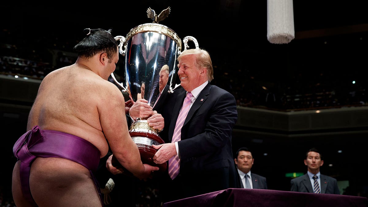 President Trump presents the "President's Cup" to the Tokyo Grand Sumo Tournament winner Asanoyama, at Ryogoku Kokugikan Stadium, on Sunday, in Tokyo. (Associated Press)