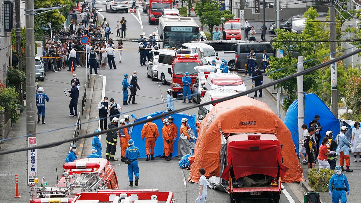 Rescuers work at the scene of an attack in Kawasaki, near Tokyo Tuesday, May 28, 2019. A man wielding a knife attacked commuters waiting at a bus stop just outside Tokyo during Tuesday morning's rush hour, Japanese authorities and media said. (Kyodo News via AP)