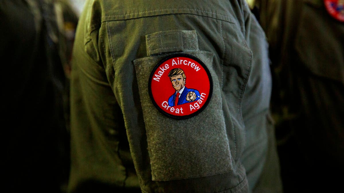 A service member wears a patch that says "Make Aircrew Great Again" as they listen to President Trump speak Tuesday aboard the USS Wasp in Japan. (Associated Press)