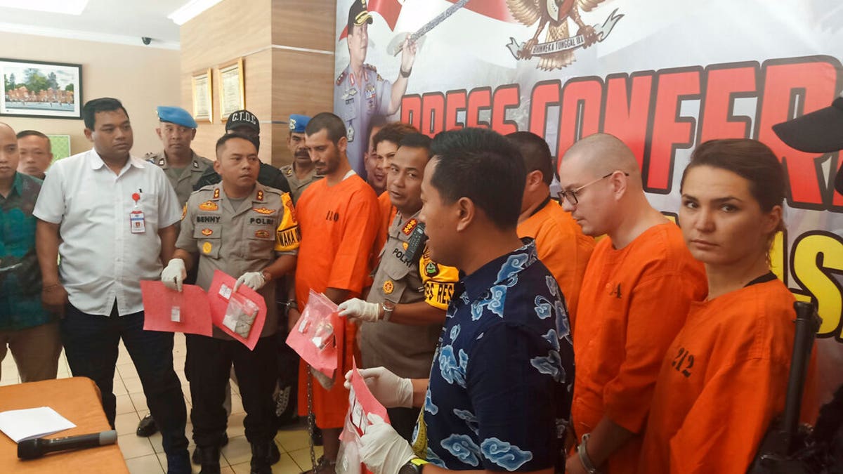 Police officers show evidence escort as they parade foreign nationals arrested for selling drugs during a press conference at the regional police headquarters in Denpasar, Bali, Indonesia, Friday, May 31, 2019. 