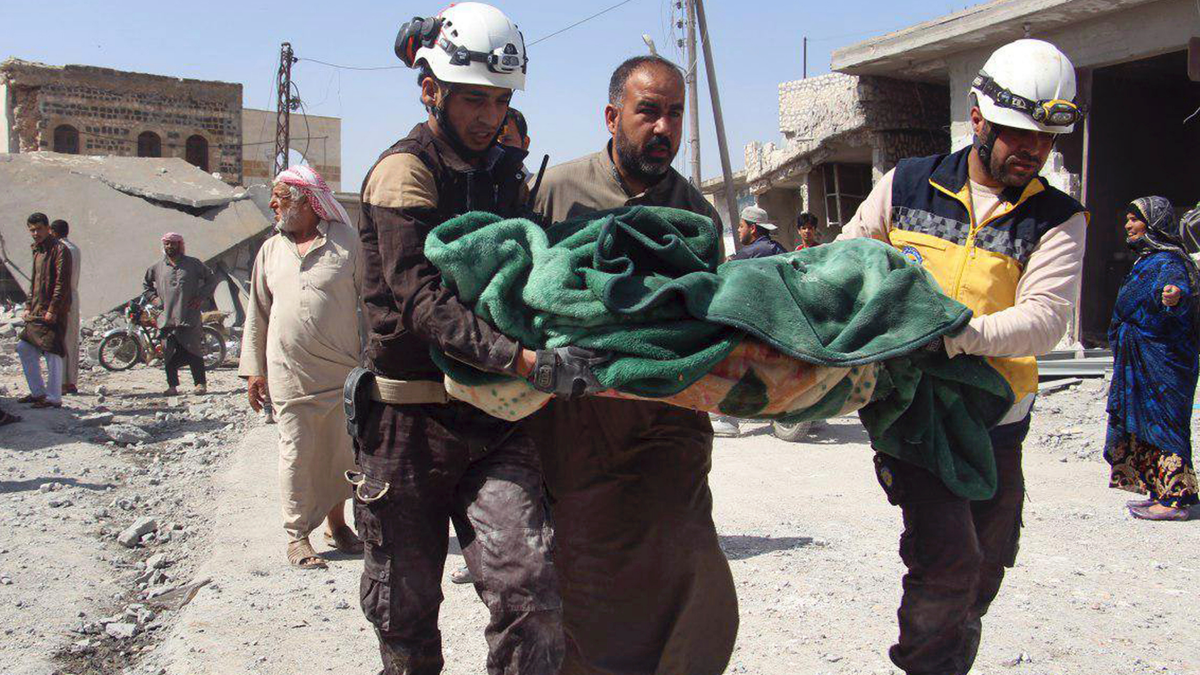 Members of the Syrian Civil Defense workers carrying a victim after a deadly airstrike hit a market killing several people in the village of Ras el-Ain, in the northwestern province of Idlib, Syria, Tuesday, May 7, 2019.? (Syrian Civil Defense White Helmets via AP)