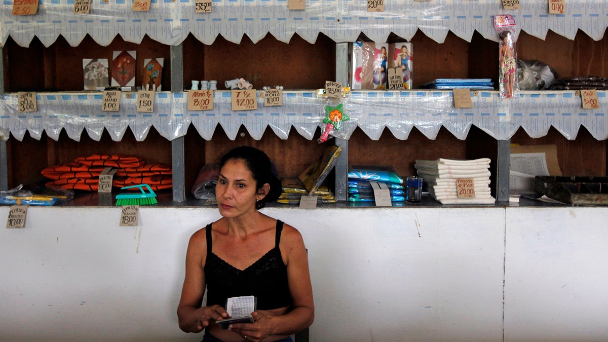 A worker holds a rationing booklet at a government-run food store called "Bodega" in Sagua La Grande, Villaclara Province, central Cuba November 8, 2009. REUTERS/Desmond Boylan (CUBA SOCIETY FOOD)