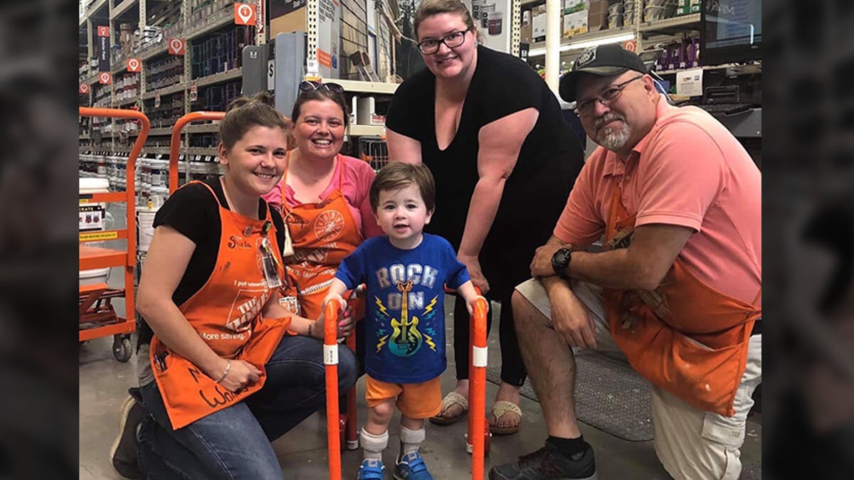 Two-year-old Logan Moore with some of the Home Depot employees who built his walker (Facebook/Jeffrey Anderson)