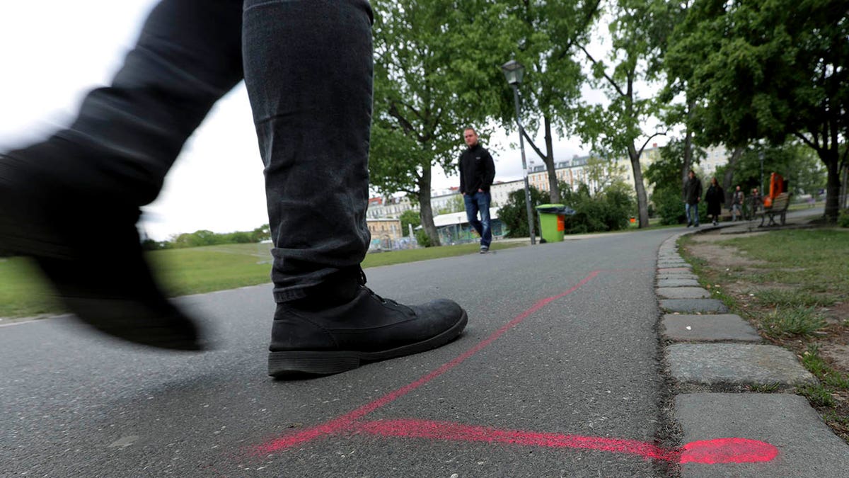 A man walks past a so called 'Drug Dealer Area' next to a traffic training course for kids at the public Goerlitzer Park in Berlin, Germany, Thursday, May 9, 2019. (AP Photo/Michael Sohn)