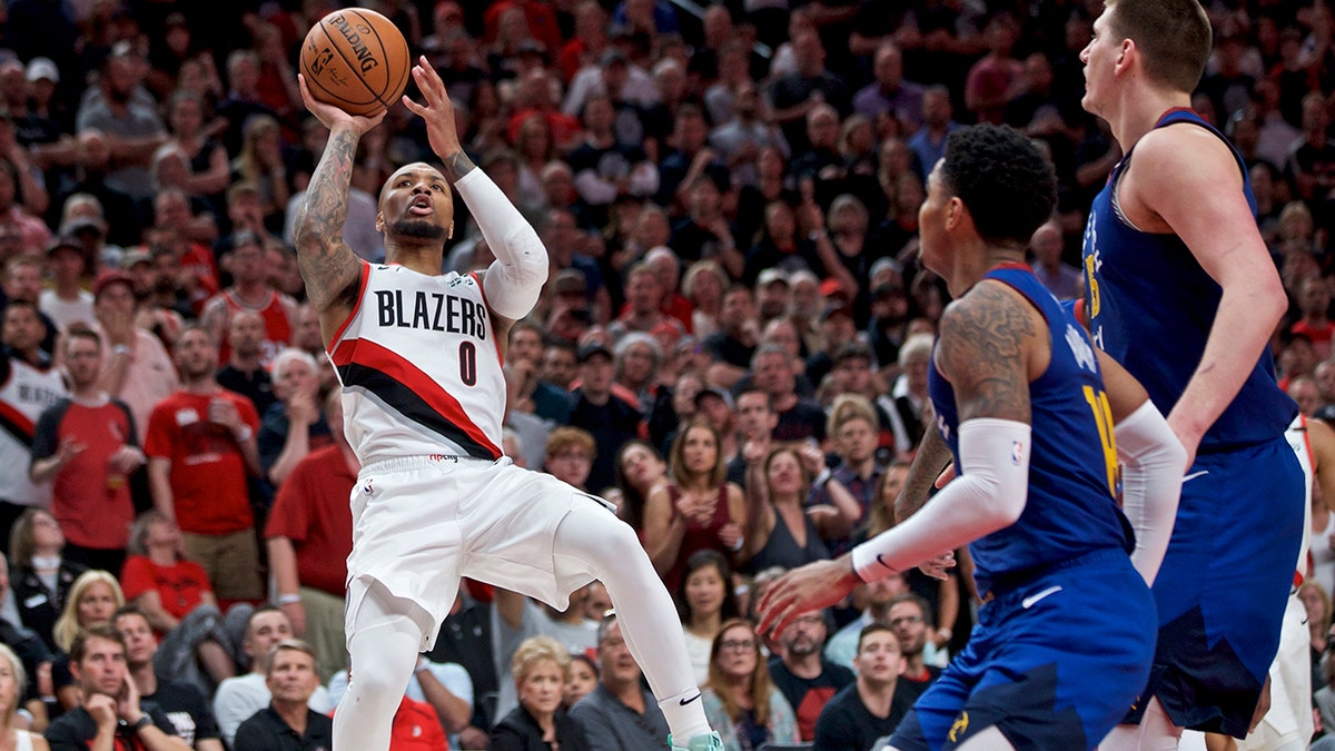 Portland Trail Blazers guard Damian Lillard, left, shoots over Denver Nuggets guard Gary Harris, center, and center Nikola Jokic, right, during the second half of Game 6 of an NBA basketball second-round playoff series Thursday, May 9, 2019, in Portland, Ore. The Trail Blazers won 119-108. (AP Photo/Craig Mitchelldyer)