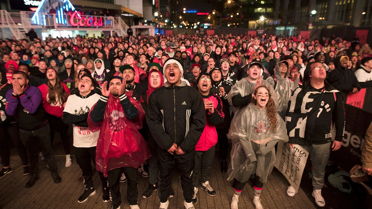 FILE - In this Sunday, May 12, 2019, file photo, basketball fans cheer for the Toronto Raptors before claiming victory over the Philadelphia 76ers outside Maple Leaf Square during their NBA Eastern Conference semifinal basketball game in Toronto. (Tijana Martin/The Canadian Press via AP, File)
