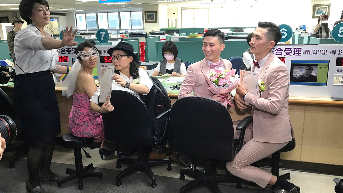 Two same-sex couples show their legal marriage certificates at the registration office in Xingyi District in Taipei, Taiwan, Friday, May 24, 2019. Hundreds of same-sex couples in Taiwan are rushing to the household registration office on the first day that a landmark decision to legalize same-sex marriage has taken effect.