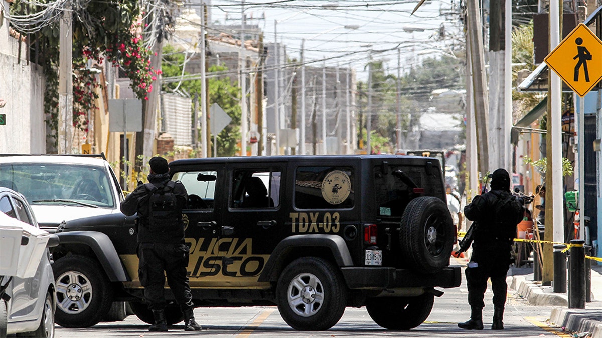 Mexican police members guarding the area where forensic service personnel worked at a clandestine grave inside a farm Saturday in Zapopan, Mexico.