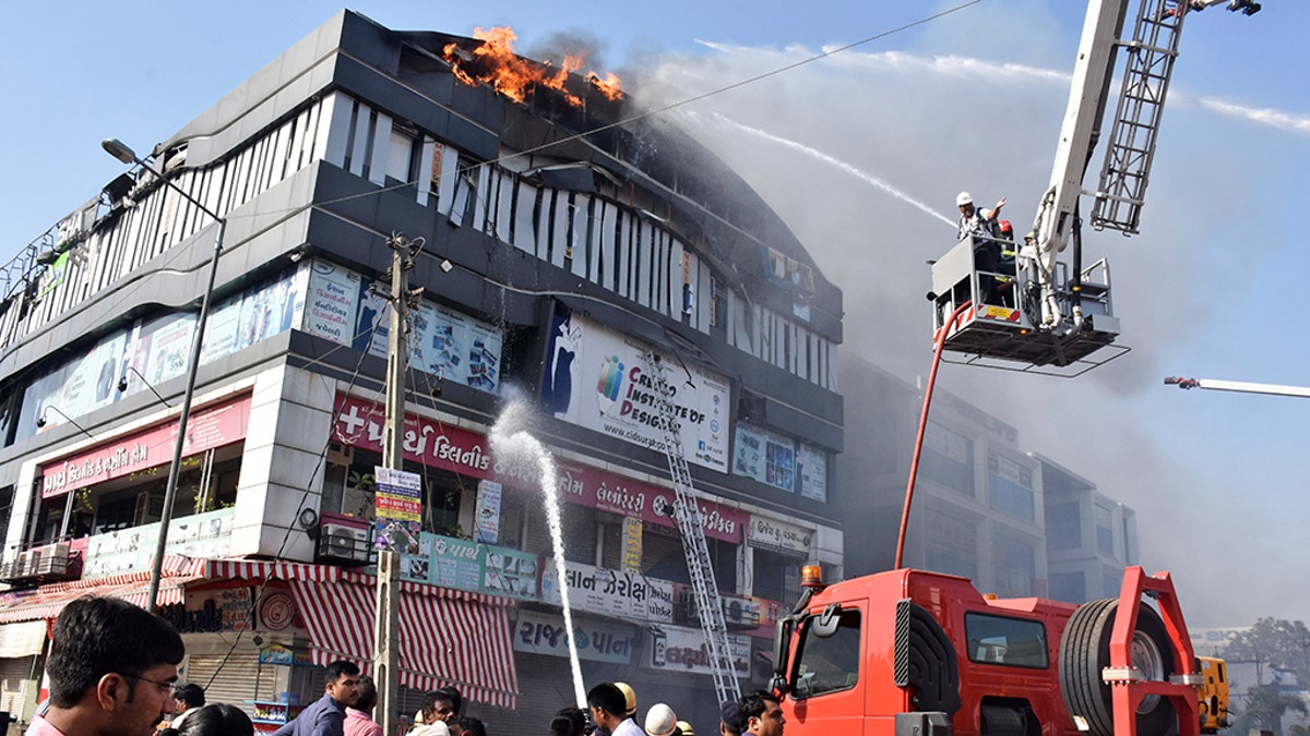 Firefighters work to douse flames on a building in Surat, in the western Indian state of Gujarat, Friday, May 24, 2019.