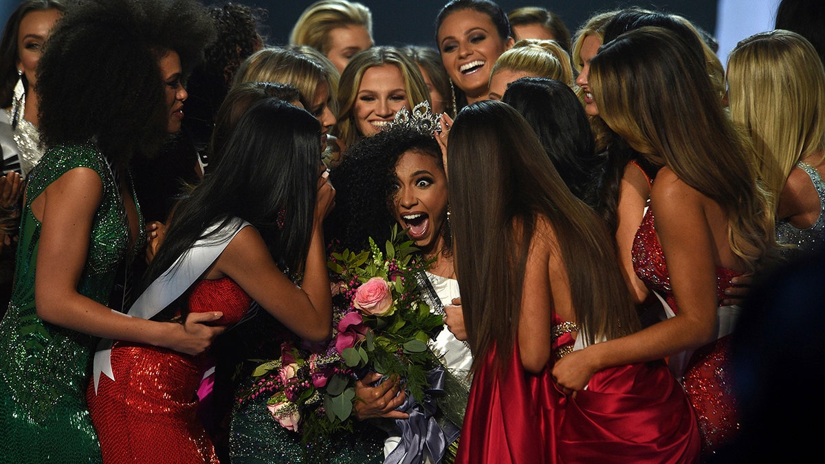 Miss North Carolina Cheslie Kryst, center, gets mobbed by her fellow contestants after winning the 2019 Miss USA final competition in the Grand Theatre in the Grand Sierra Resort in Reno, Nev., on Thursday, May 2, 2019. Kryst, a 27-year-old lawyer from North Carolina who represents some prison inmates for free, won the 2019 Miss USA title Thursday night in a diverse field that included teachers, nurses and members of the military. (Jason Bean/The Reno Gazette-Journal via AP)