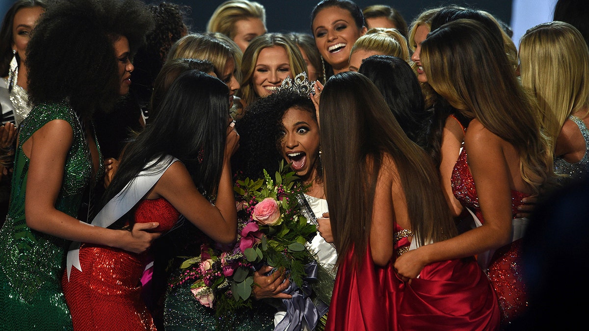 Miss North Carolina Cheslie Kryst, center, gets mobbed by her fellow contestants after winning the 2019 Miss USA final competition in the Grand Theatre in the Grand Sierra Resort in Reno, Nev., on Thursday, May 2, 2019. Kryst, a 27-year-old lawyer from North Carolina who represents some prison inmates for free, won the 2019 Miss USA title Thursday night in a diverse field that included teachers, nurses and members of the military. (Jason Bean/The Reno Gazette-Journal via AP)
