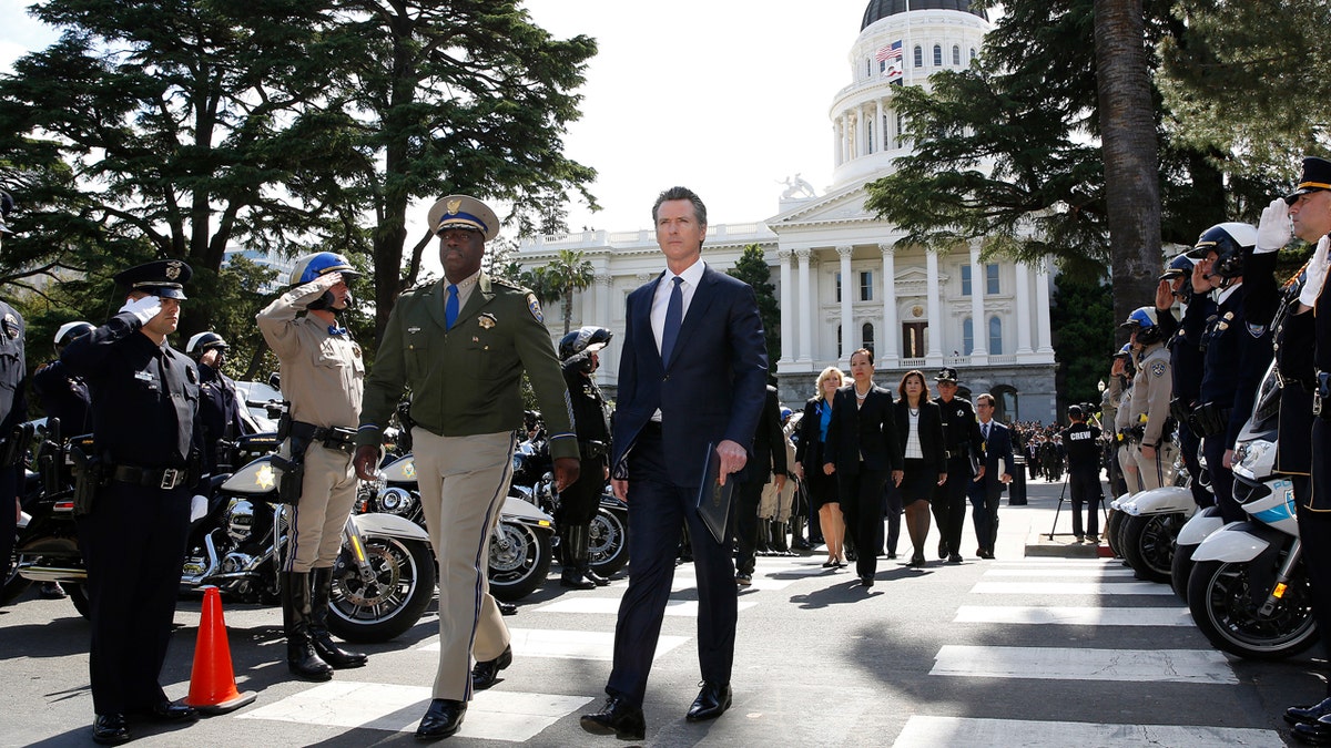 Gov. Gavin Newsom, right, and California Highway Patrol Commissioner Warren Stanley, left, pass a line of law enforcement officers as they walk to the California Peace Officers Memorial, Monday, May 6, 2019, in Sacramento, Calif.
