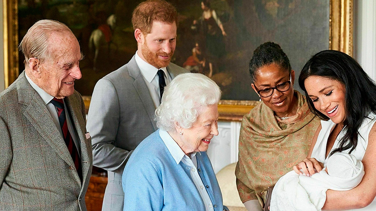 In this image made available by @SussexRoyal on May 8, 2019, Britain's Prince Harry and Meghan, Duchess of Sussex, joined by her mother Doria Ragland, show their new son to Queen Elizabeth II and Prince Philip at Windsor Castle, Windsor, England. Prince Harry and Meghan have named their son Archie Harrison Mountbatten-Windsor.