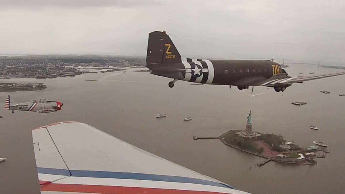 The Geico Skytypers and a Douglas C-47 military transport plane fly by the Statue of Liberty Thursday.
