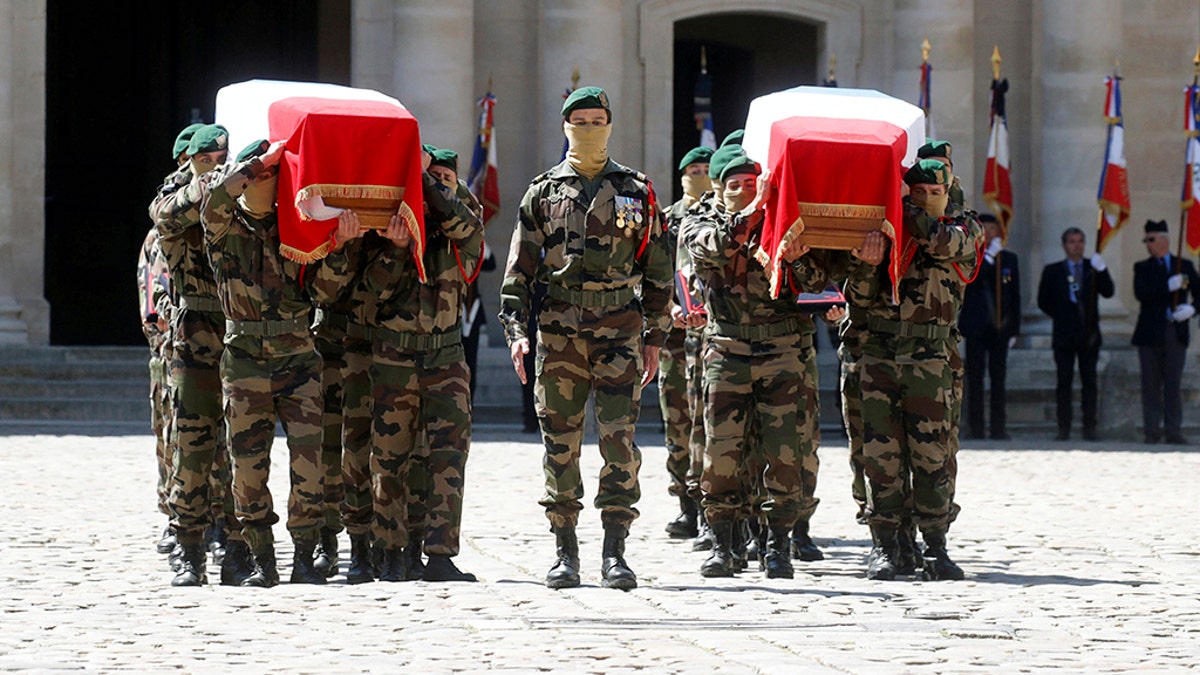 Special forces soldiers carry the flag-drapped coffins of late special forces soldiers Cedric de Pierrepont and Alain Bertoncello, who were killed in a night-time rescue of four foreign hostages including two French citizens in Burkina Faso last week, during a national tribute at the Invalides, in Paris, Tuesday, May 14, 2019. France is honoring two special forces officers killed in an operation that freed four hostages held in Burkina Faso.