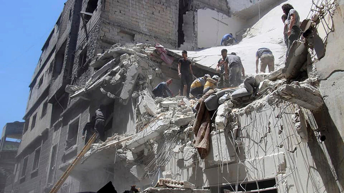 This photo provided by the Syrian Civil Defense White Helmets, which has been authenticated based on its contents and other AP reporting, shows Civil Defense workers inspecting a damaged building after an airstrike by Syrian government forces, in the town of Ariha, in the northwestern province of Idlib, Syria, Monday, May 27, 2019.